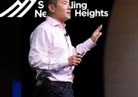Scaling New Heights Presenter in front of Logo